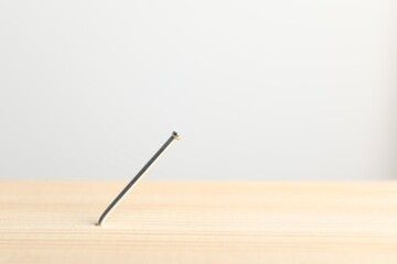 Metal nail in wooden plank on light grey background, closeup. Space for text