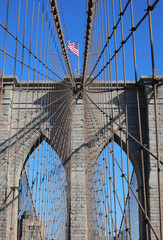 Obraz premium Waving American Flag on the top of Tower of Brooklyn Bridge and many steel cables