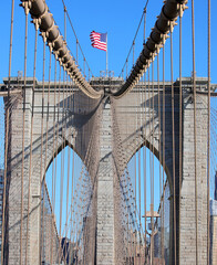 Fototapeta premium American Flag on the top of Brooklyn Bridge and steel cables in New York City in USA