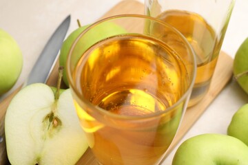 Fresh cider in glass, bottle, apples and knife on table, closeup