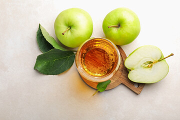 Fresh cider in glass and apples on beige table, flat lay