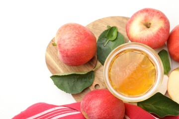 Fresh cider in glass, apples and green leaves on white table, flat lay