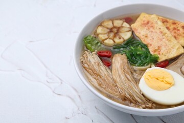 Tasty ramen with enoki and king oyster (eryngii) mushrooms on white table, closeup. Space for text