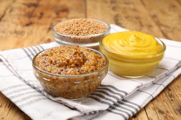 Different types of mustard on wooden table, closeup