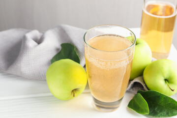 Fresh cider in glass, bottle and apples on white wooden table, closeup