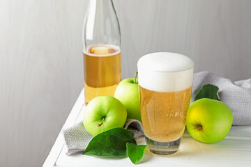 Fresh cider in glass, bottle and apples on white wooden table, closeup