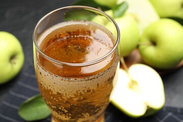 Fresh cider in glass and apples on table, closeup
