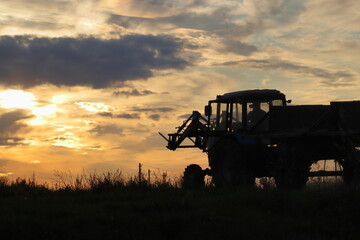 Tractor with front forklift in field against orange sunset © MIKHAIL BATURITSKII	