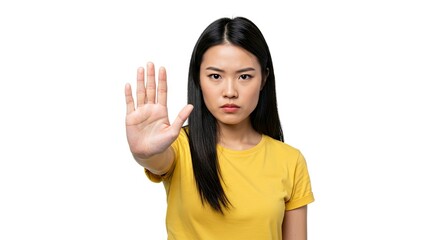 Asian woman in yellow shirt with stern expression holding up a hand in a stop gesture on a white background