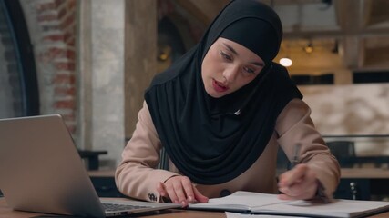 Arabian muslim business woman in hijab businesswoman working in office multitask talking phone browsing laptop online service with papers documents busy female girl finishing smartphone call chatting - Powered by Adobe