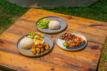 Delicious Indonesian satay and rice dishes on a rustic wooden table for a delightful meal