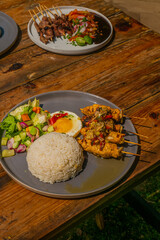 Delicious Indonesian satay and rice meal, ready to enjoy on a rustic wooden table outdoors
