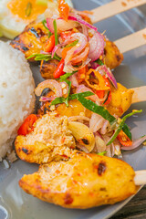 Delicious grilled chicken satay skewers with fresh vegetable toppings and fluffy white rice
