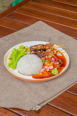 Delicious grilled satay marrangi with rice and vibrant fresh salad on a beautifully set plate