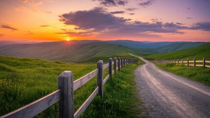 Obraz premium Idyllic country road at sunset with a wooden fence and rolling hills