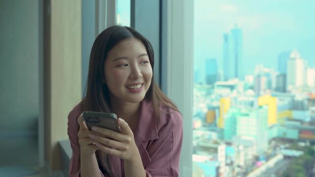 Happy young woman sitting on sofa holding phone smiling enjoying using mobile apps for shopping, having fun playing games, chatting on social media at office