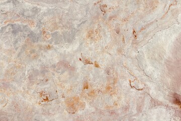 Natural stone texture with earthy tones of gray and rusty orange, showcasing rough surface patterns and organic details, ideal for backgrounds or design elements.