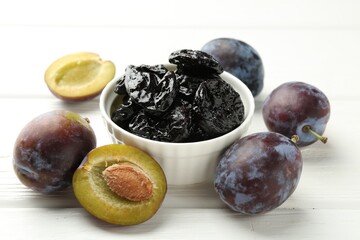 Dried prunes and fresh plums on white wooden table, closeup