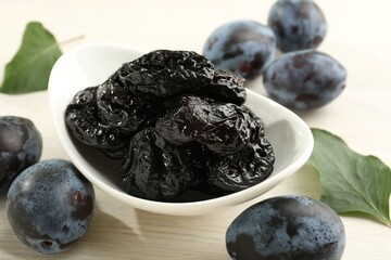 Dried prunes and fresh plums on wooden table, closeup