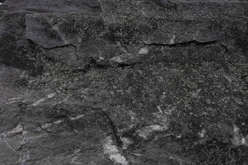 High-resolution close-up of a dark stone surface with natural rough texture and layered structure. Ideal for use in design, architecture, background, or material references