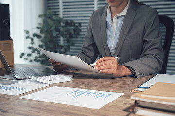 Business Professional in Action: A focused professional, meticulously reviews financial documents, her dedication palpable in the quiet of a modern office. Her analytical mind, poised with a pen.