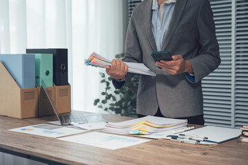 Professional in a Corporate Setting: A focused professional meticulously manages documents and utilizes a calculator within a well-organized office environment.