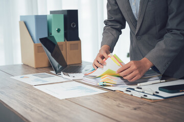 Organized Workflow: A focused professional meticulously manages an array of documents within a modern office setting. The image evokes a sense of efficiency, precision.