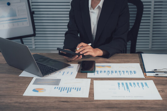 Calculating Business Insights: An accountant meticulously crunches numbers, surrounded by financial documents, a laptop, and a smartphone.