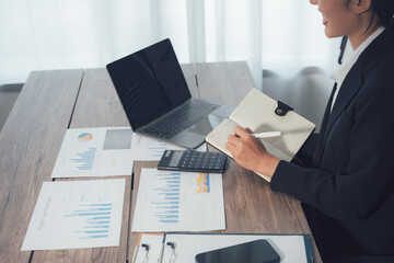 Focused Work: A professional woman diligently works at her desk, engrossed in analyzing data and making notes, showcasing a scene of focused concentration and productivity.