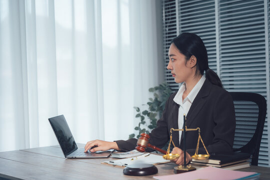Legal Professional: Focused lawyer, engrossed in their work with a laptop, the scales of justice and a gavel emphasizing dedication and the pursuit of truth and fair judgment.