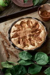 Homemade traditional apple pie with golden crust served on a rustic wooden table surrounded by fresh green apples in a cozy garden setting