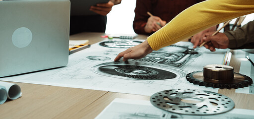 Engineers collaborate over detailed technical drawings and blueprints in a modern workspace, utilizing tools for innovative project planning and design analysis. SACTR