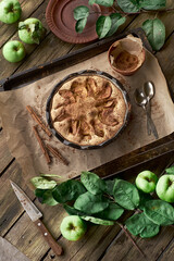 Homemade traditional family recipe classic apple pie served on a rustic table in a garden setting styled with organic apples, rustic wood textures, in a natural warm autumn light in a slow life style