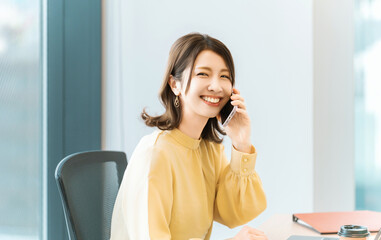 スマートフォンで話す笑顔の女性・ビジネスウーマン