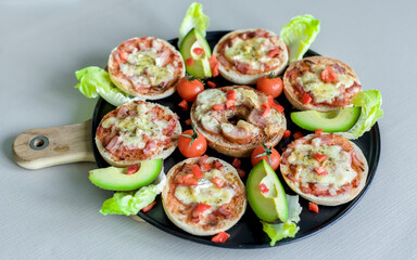 Mini Bagel Pizzas with Fresh Avocado, Brie, Ham, Cheddar and Cherry Tomatoes on Black Tray, Wooden Board