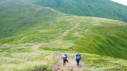 Two women with large backpacks walking along a mountain trail, hiking and trekking, travel, outdoor recreation