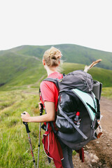 young woman's view back with a large backpack looking at mountain ranges and peaks, in the mountains, hiking, travel, atmospheric photo