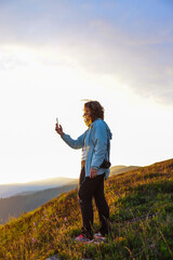 woman taking photos of the landscape at dawn in the mountains, travel, impressions, social media