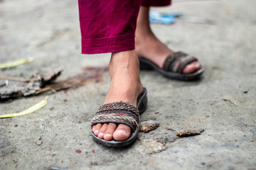 Closeup of a persons feet wearing sandals on a concrete surface