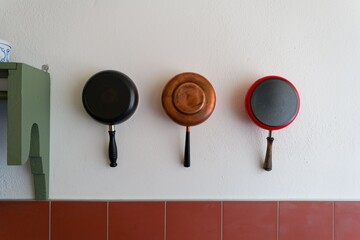 Copper and red frying pans on kitchen wall