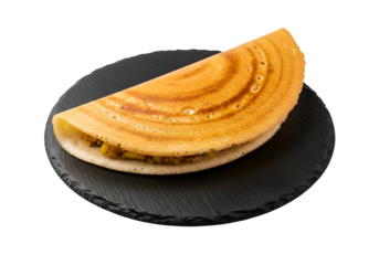 A golden-brown, circular Indian crepe, filled with savory ingredients, sits on a dark slate plate against a black background.
