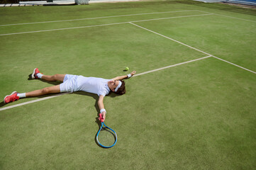 Tennis Player Sprawled on Court After Intense Match on Grass Surface