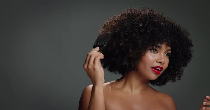 Smile, black woman and comb for hair care in studio for detangling, natural growth and afro volume. Happy, female person and tools for textures, maintenance and scalp treatment on gray background