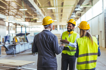 Team of Engineers Collaborating in a Modern Industrial Workspace Featuring Safety Gear