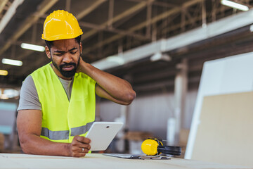 Construction Worker Experiencing Neck Pain While Reviewing Plans on a Tablet