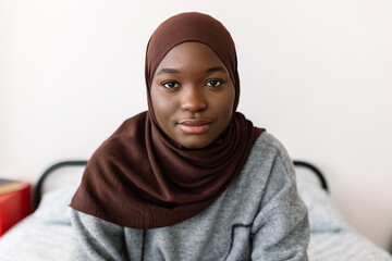 Portrait of young serious african woman in muslim headscarf at home. Proud of religion and islamic people concept