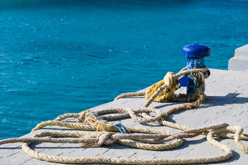 A blue anchor is tied to a rope on a dock