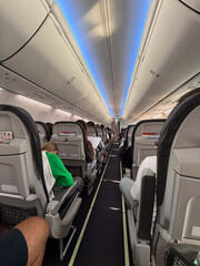 Inside view of airplane cabin with passengers seated during flight. Travel experience, aviation comfort and in-flight atmosphere of commercial airline journey.