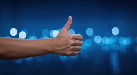 Thumbs Up Gesture: A person's hand displays a thumbs-up gesture against a backdrop of ethereal blue bokeh, offering a message of approval and agreement.