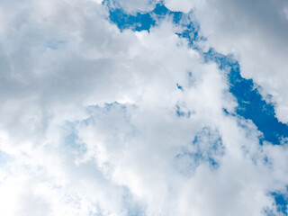 Obraz premium Bright cloudy sky with fluffy white clouds and patches of clear blue, natural abstract background for weather and atmosphere concepts